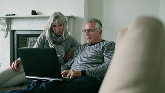 一对老年夫妇在家里用笔记本电脑视频素材