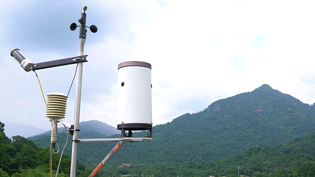 气象气象站天线与气象传感器，灰色多云天空和森林背景。视频下载