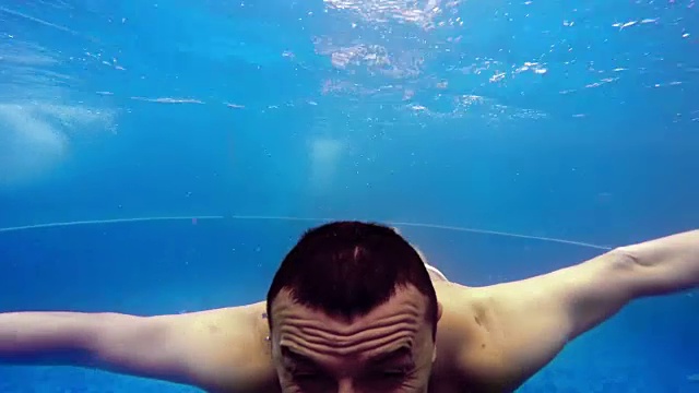 Under water shot of a man jumping in a pool, uhd stock video在水下拍摄的一个人跳在一个游泳池，uhd stock video视频下载