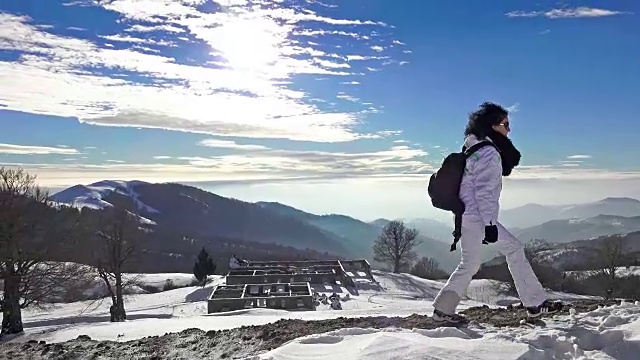 背包女徒步旅行者在危险的冰雪覆盖的山面地平线。超高清4K摄像机库存视频视频素材
