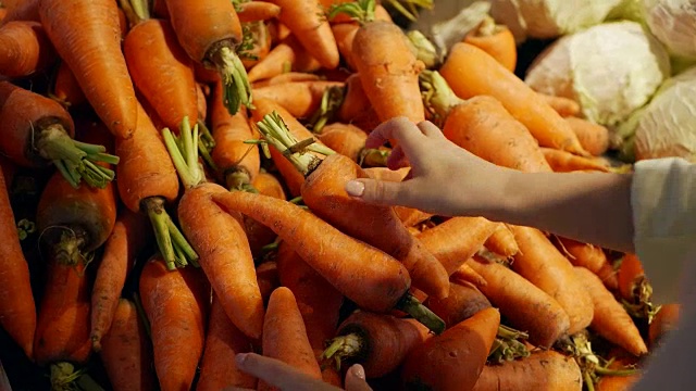 在超市里，女人用手挑选胡萝卜视频素材