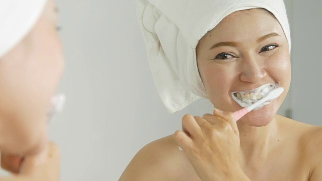 一个穿着浴巾的女人在浴室里用镜子刷牙视频下载