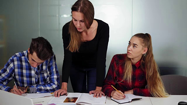 三个学生坐在一起做作业，一个女孩在听写，另外两个学生在写。Slowmotion拍摄视频素材