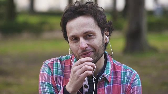 一个安静的男人在公园里用耳机打电话视频素材