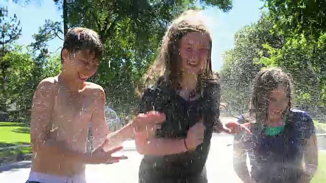 夏天的午后，一群青少年朋友在消防栓上嬉笑跳跃，溅起水花视频素材