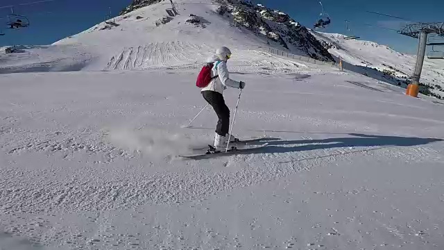一个女人在滑雪道上滑雪，太阳和雪山。视频素材
