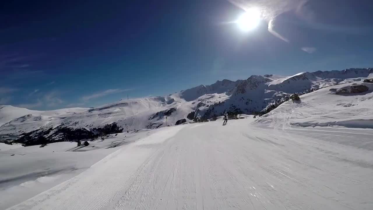 一个女人在滑雪道上滑雪，太阳和雪山。视频素材