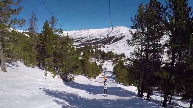 滑雪者站在滑雪缆车上，在雪地里打滚，周围是森林。视频素材