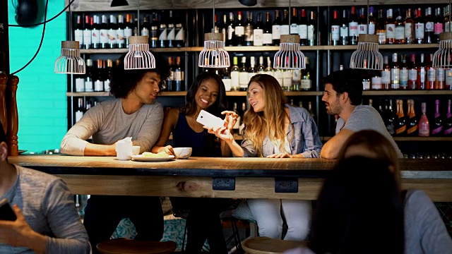 四人约会的情侣一边喝咖啡，一边在智能手机上看照片视频素材