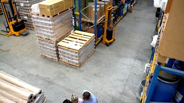 团队在仓库的货架之间开会，大家都在看剪贴板上的文件视频下载
