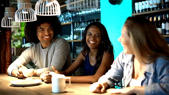 一对快乐的黑人夫妇和一个朋友一起喝着咖啡笑着视频素材