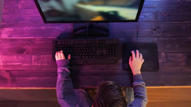 俯视图一个小男孩在他的电脑上玩电子游戏视频素材