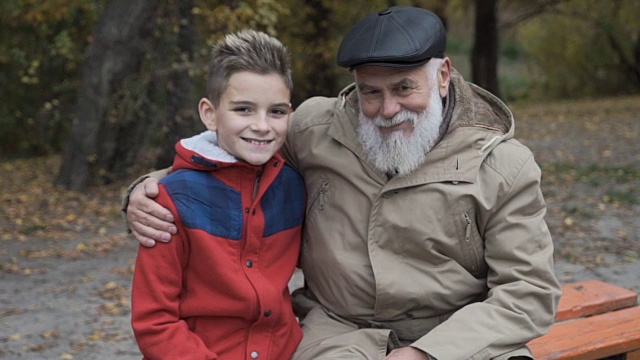 快乐的爷爷和孙子在公园的长椅上视频素材