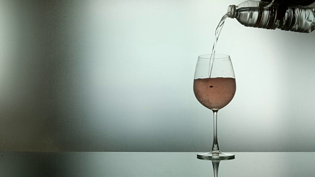 在柔和的自然光线背景下，在葡萄酒杯中完成和混合水。用文案空间做广告和品牌推广视频下载