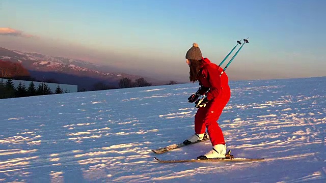 日落滑雪。女滑雪者沿着沿着山坡的滑雪路线滑行。视频下载