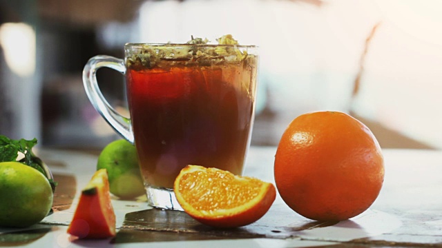 一杯加了сhrysanthemums和橘子的冰茶，放在深色的木桌上视频下载