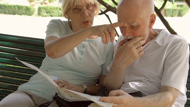 家庭享受假期。老年人坐在公园的长椅上研究城市地图寻找景点视频素材