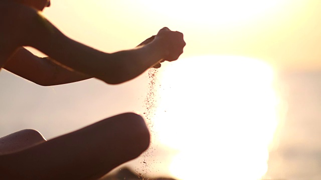 夕阳西下，沙滩上的沙子从她手中滑落视频素材