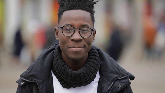 寒冷的秋天，一个非洲人在城市街道上微笑的肖像视频素材