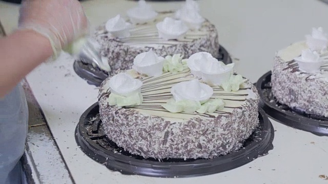 厨师亲手制作蛋糕。糕点管在蛋糕上涂上蛋白酥皮。视频下载