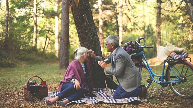 一对浪漫的老夫妇坐在草地上，一边野餐一边放松。视频素材