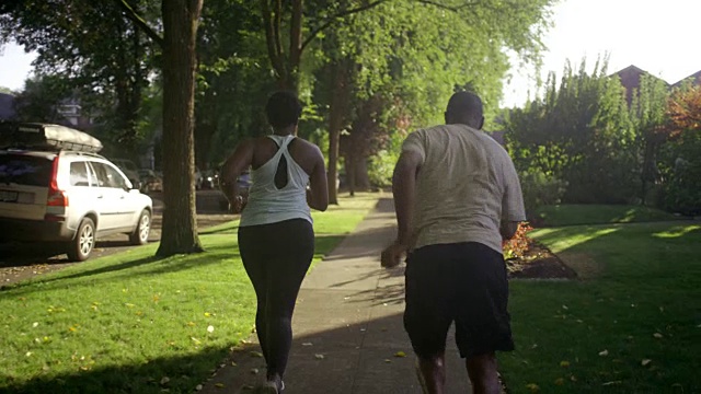 一位年轻女子在晨跑时和父亲挤在一起。视频素材