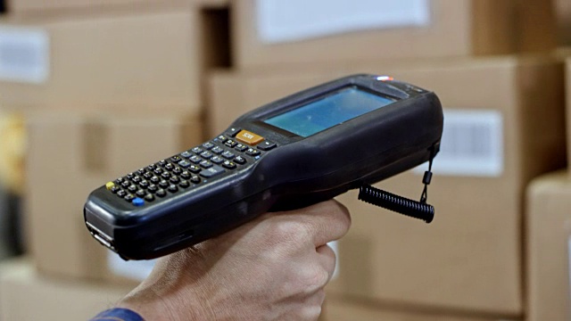 一个男人用手持扫描仪扫描仓库里的包裹视频素材