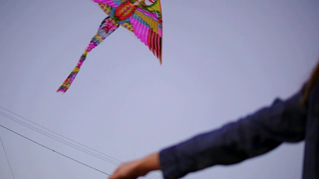 女人的手在晚上拿着五颜六色的风筝的特写。彩色的风筝在天空的背景。Slowmotion拍摄视频素材