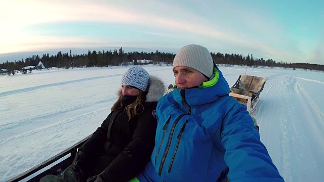 图:在冰雪覆盖的拉普兰，一对夫妇乘坐驯鹿雪橇旅游景点视频下载