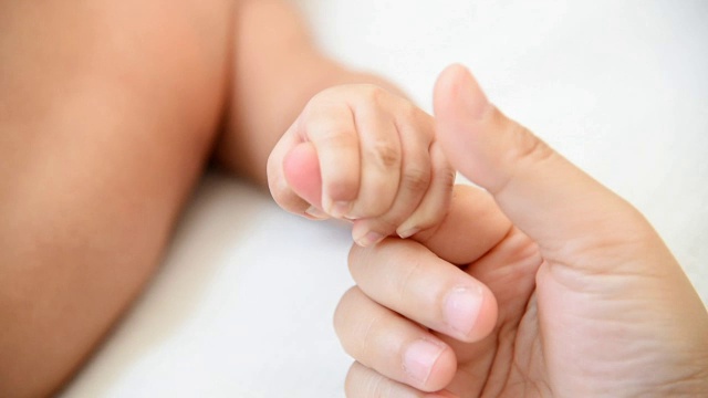 母亲手牵着新生婴儿的手，慢动作视频素材