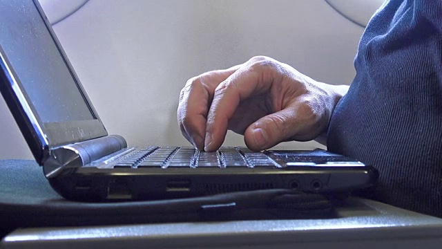 一名男子在飞机上用手提电脑打字视频素材