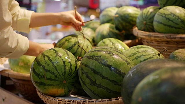 在超市里，女人用手挑选新鲜的西瓜视频素材
