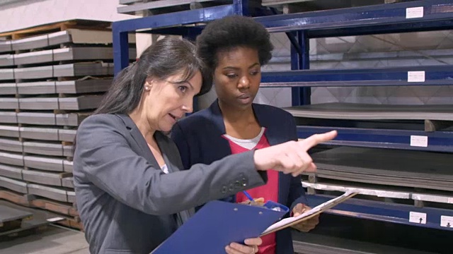 在工厂里，女商人们在写字板上讨论视频素材