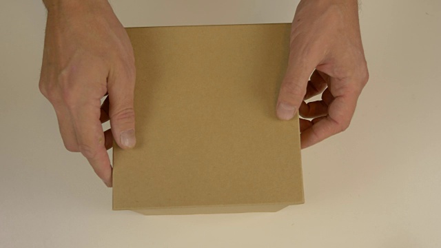 空的棕色纸箱。男人的手靠近顶部礼盒。空礼盒。柔和的背景。礼物盒子。前视图。视频下载