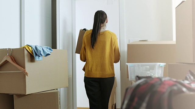 一个女人带着装着东西的纸箱来到她的新公寓视频下载
