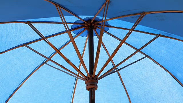 室外的蓝色遮阳伞，在泳池的水面上反射阳光视频下载