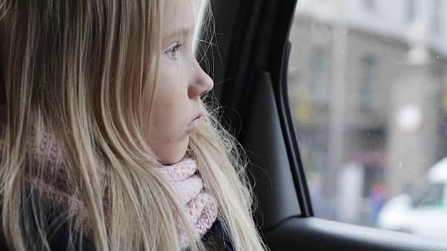 一个金发小女孩坐在车后座上。视频素材