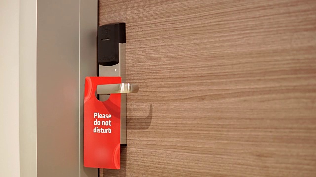 酒店客房客人在防盗门把手上插入“请勿打扰”字样视频素材