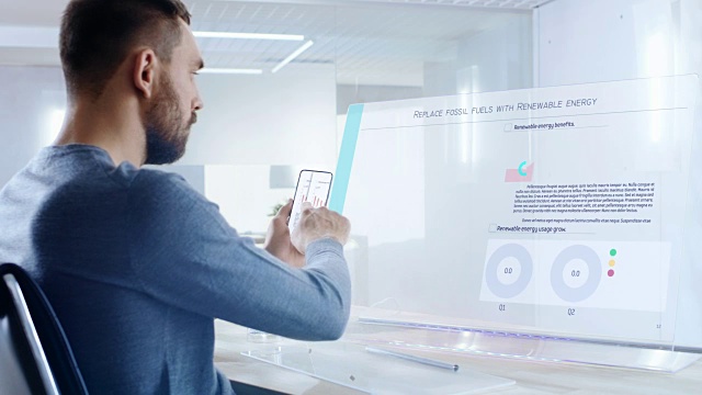 在不久的将来，可再生能源专家从触屏智能手机到他的透明显示电脑，敲击和分享数据。屏幕显示交互式信息图形与彩色图形和数据。视频素材