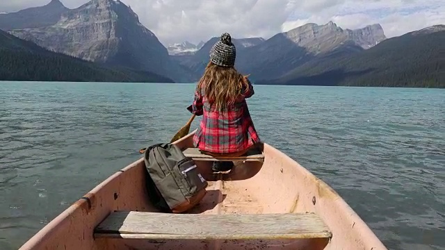 一个年轻女子划着独木舟穿过高山湖泊。视频素材