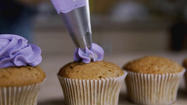 用紫色奶油装饰纸杯蛋糕。用烹饪包，糖果机做松饼视频素材