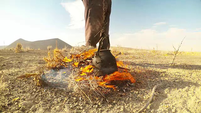 有人正在用水壶加热茶在桩子上从一个干草的背景火山口火山近视频下载