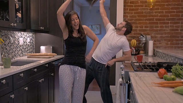 成功的快乐的男人和女人在他们的现代厨房里一起跳舞视频素材