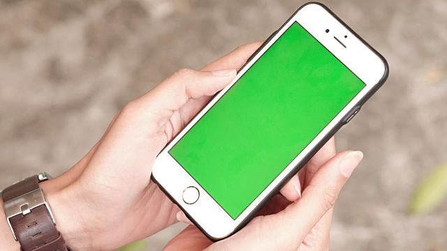 一个女人拿着一个绿色屏幕的智能手机视频下载