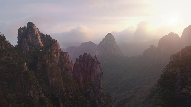 一架无人机向后飞行，展示了中国黄山山下山峰的细节。视频下载