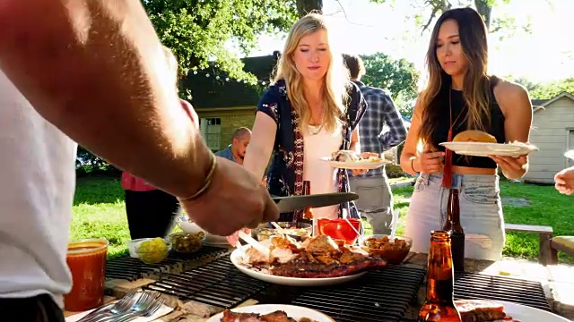 微软的朋友在夏天的晚上在后院提供烧烤服务视频素材