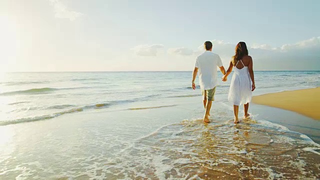 一对情侣在日落时分的海滩上散步视频素材