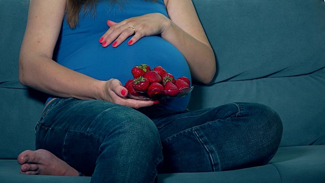 孕妇用手吃着樱桃浆果，抚摸着肚子视频素材