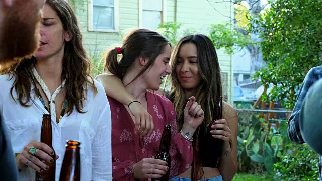 夏天的晚上，一个微笑着的女人挽着朋友在后院的聚会上闲逛视频素材