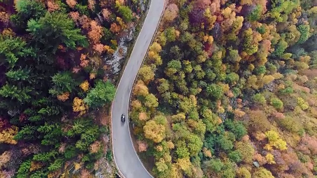 空中鸟瞰汽车行驶在五彩缤纷的秋天森林道路上。秋天有橙、绿、黄、红的树林。山区街道道路的建立。4k无人机飞行直线下降建立拍摄视频下载